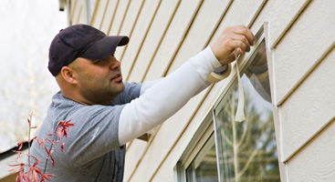 Worker Taping Off Home Exterior for Painting